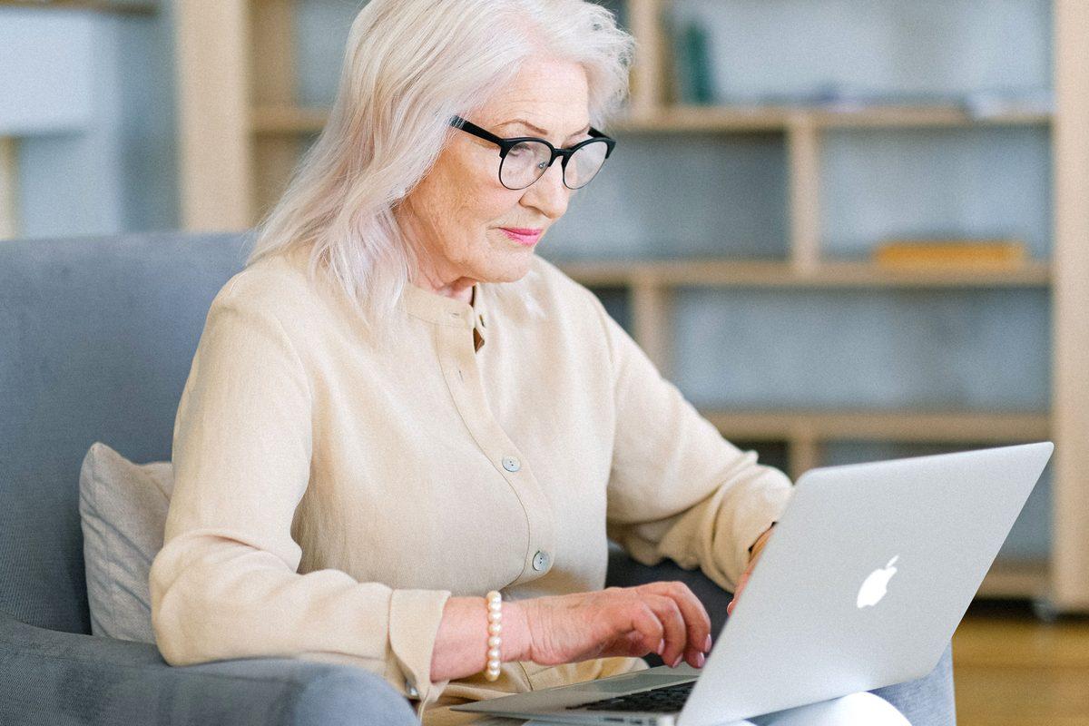 Older woman comfortably using a laptop at home